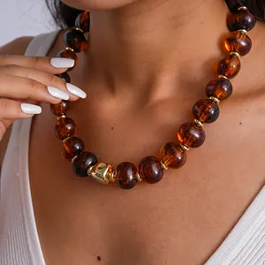 Primo piano di una collana retrò con perle in acrilico ambrato e accento in metallo oro.