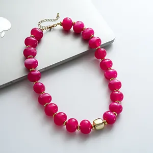 Vista dettagliata delle perle in acrilico marmorizzato fucsia e accenti dorati su collana retrò
