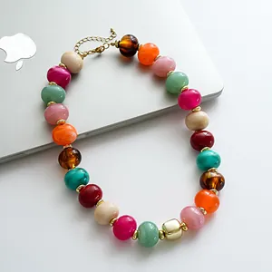 Primo piano di una collana retrò con perle di acrilico marmorizzate su uno sfondo laptop