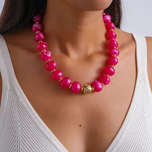 Primo piano di una collana di perle acriliche rosa marmorizzate con tocchi dorati.