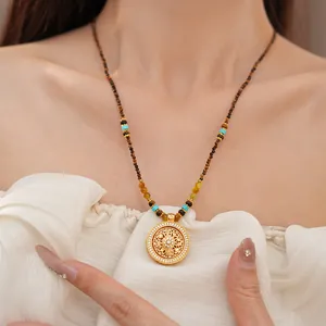 Detail van neo-Chinese vergulde ketting met bloemenhanger en natuurlijke tijgeroog kralen