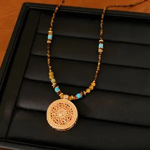 Gedetailleerde close-up van een gouden kralenketting met een verfijnde bloemenhanger