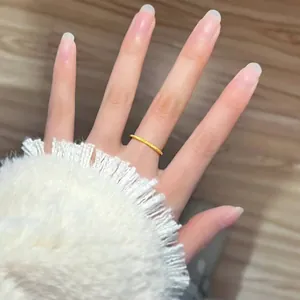 Close-up detail of minimalist gold frosted stardust titanium steel ring worn on finger