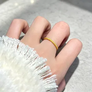Detailed view of a minimalist gold frosted stardust titanium steel ring on finger.