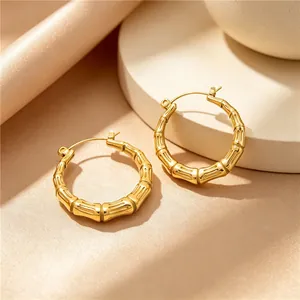 Close-up detail of gold-plated bamboo joint hoop earrings on minimalist pedestal