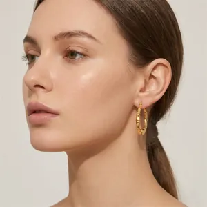 Detailed view of gold-plated bamboo joint hoop earrings on a female model.