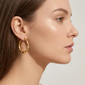Close-up of elegant gold-plated titanium steel bamboo joint design hoop earring on model