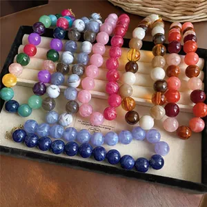 Close-up of vibrant acrylic beaded necklaces with marble swirl patterns in a jewelry tray
