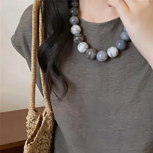 Close-up of chunky marble pattern acrylic bead necklace on a woman for holiday style