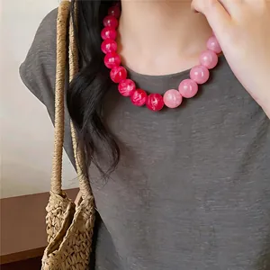 Detailed view of vibrant pink gradient acrylic round beaded necklace worn by a model