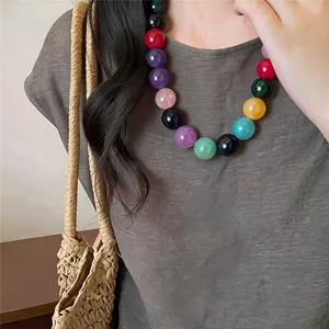 Detailed macro view of vibrant dopamine acrylic beaded necklace on model's neck.