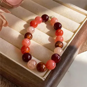 Detailed view of vibrant acrylic beaded bracelet with red and pink tones in jewelry box