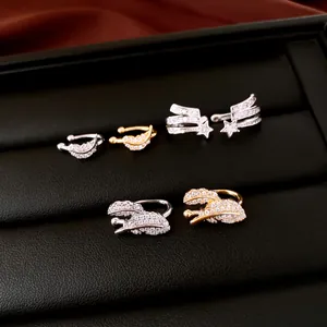 Detail of shiny zircon star and wing ear cuffs in silver and gold finishes.