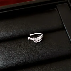 Macro detail of a sparkling silver zirconia leaf-shaped ear cuff on black jewelry tray