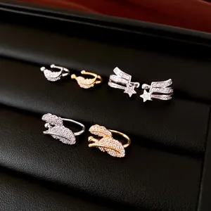 Detailed view of zircon ear cuffs with star, moon, and feather designs on a black tray