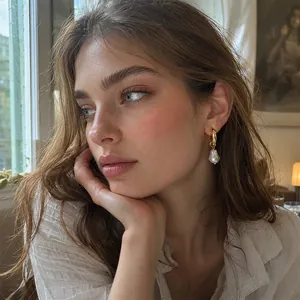 Side profile of a woman wearing gold hoop earrings with baroque imitation pearl drops