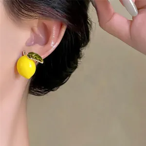 Close-up detail of 14k gold plated lemon enamel stud earrings worn on ear