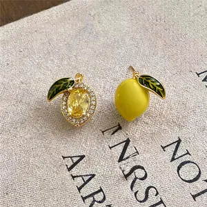 Macro view of 14k gold-plated lemon earrings with yellow crystal and green enamel leaves