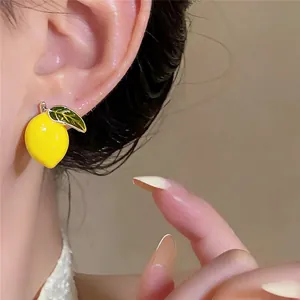 Close-up of a 14k gold plated lemon stud earring with vibrant yellow enamel finish