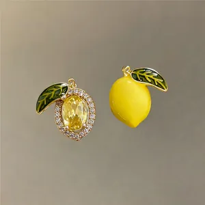 Detail view of 14k gold plated lemon pendants with yellow zircon and green enamel leaves.