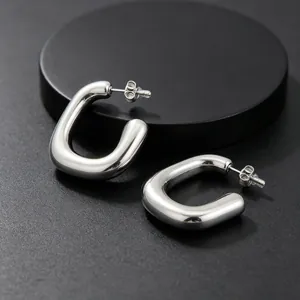 Gros plan de boucles d'oreilles en acier inoxydable poli en forme de U sur fond noir