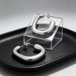 Vue macro de boucles d'oreilles en acier inoxydable poli en forme de U sur plateau noir