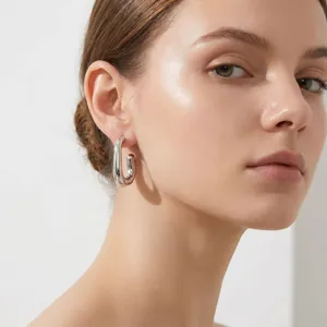 Gros plan d'un mannequin portant des boucles d'oreilles créoles en forme de U en argent.