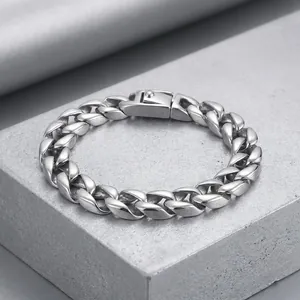 Primer plano de pulsera de eslabones cubanos plateados con cierre en superficie rugosa