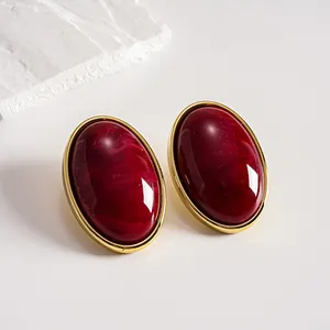 Detailed view of vintage marbled red acrylic oval stud earrings with gold frame