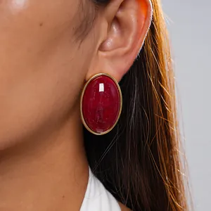 Close-up of vintage red marbled acrylic oval stud earrings with elegant gold border