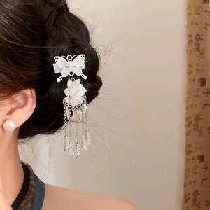 Detail view of a vintage silver butterfly tassel hair clip worn on braided dark hair.