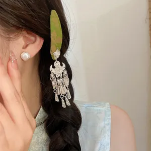 Detailed macro view of vintage silver floral tassel hair clip worn on braided hair