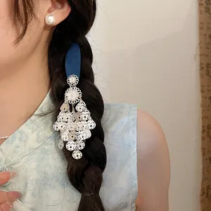 Detailed view of a vintage blue flower tassel hair clip worn on a model's braided hair