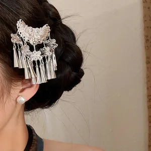 Detailed view of a vintage silver butterfly tassel hair clip on black hair.