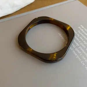 Close-up of a vintage tortoiseshell resin bangle with a square shape on a grey surface