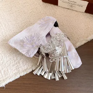 Dettaglio macro dell'elegante molletta etnica con fiocco in tessuto viola e nappe argento