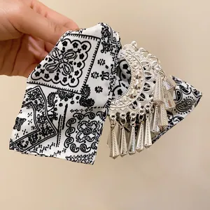 Detailopname van etnische haarclip met bandana print strik en zilveren bedeltjes