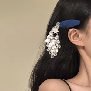 Dettaglio di un fermaglio per capelli etnico con nappa argentata su lunghi capelli neri