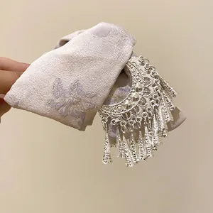 Dettaglio di fermaglio per capelli a fiocco stile etnico con frange metalliche