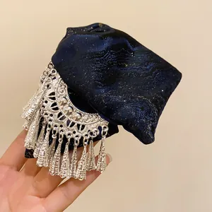 Detail of ethnic style hair clip with navy jacquard bow and silver tassel ornaments.