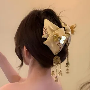 Dettaglio di un fermaglio per capelli a fiocco etnico con farfalle dorate e sonagli