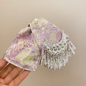 Dettaglio di una molletta per capelli etnica con frange argentate e fiocco a fantasia.