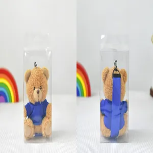 Vista frontal y trasera de un lindo llavero de peluche de oso marrón en caja clara