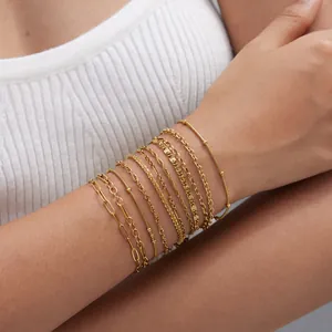 Detalle de varios brazaletes de cadena de acero inoxidable dorados apilados en la muñeca