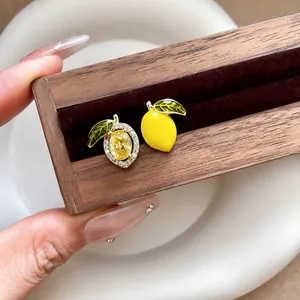 Asymmetric lemon earrings with yellow zircon and green enamel in 14k gold plating.