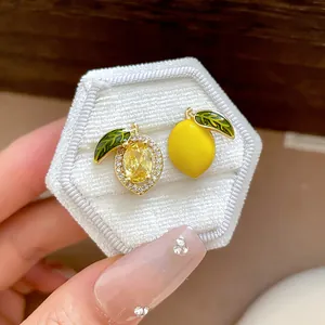 Macro detail of asymmetrical lemon stud earrings with yellow zircons and enamel finish