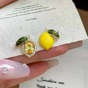 Detail view of 14k gold plated zircon and enamel lemon asymmetrical stud earrings.