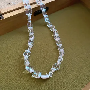 Détail d'un collier en perles de verre transparent avec accents blancs en boîte bois
