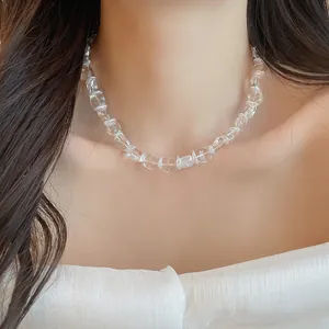 Détail d'un collier de perles en verre transparent minimaliste porté par un mannequin