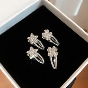 Detailaufnahme von vier silbernen Strass-Haarclips mit Sternen und Kleeblattmotiven
